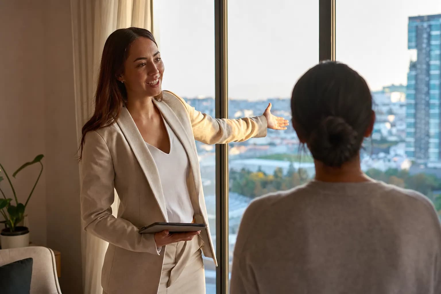 Maklerin zeigt einer Interessentin eine helle Wohnung mit Blick auf die Stadt