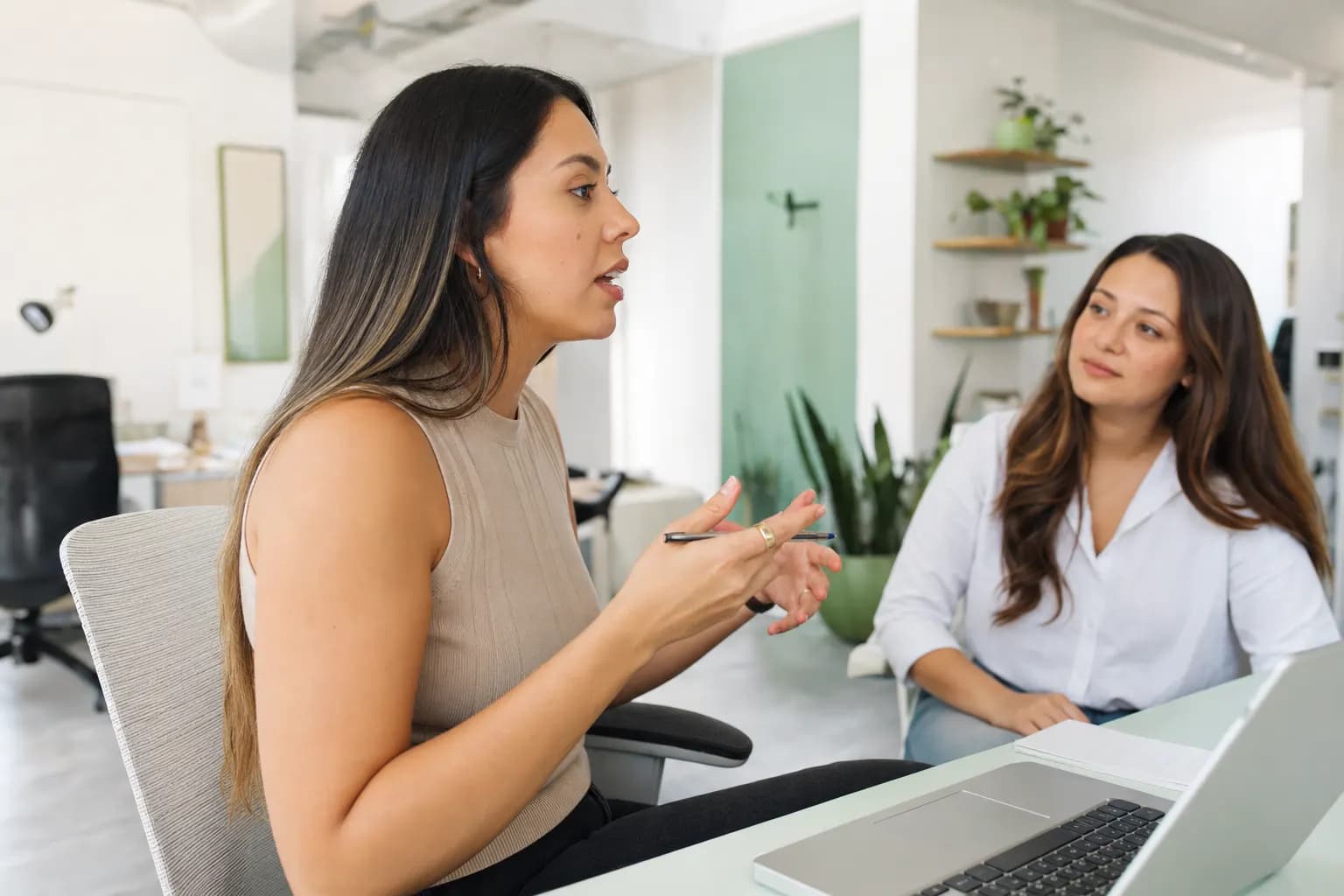 Recruiterin im hellen Agentur-Büro im Gespräch mit Kollegin.